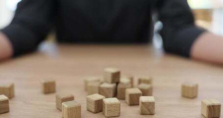 Woman scatters small wooden cubes with alphabet letters. Neat hands of female person with nude manicure and blocks for making words on table surface slow motion - Powered by Adobe