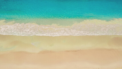 Beach and azure sea with waves from top view.