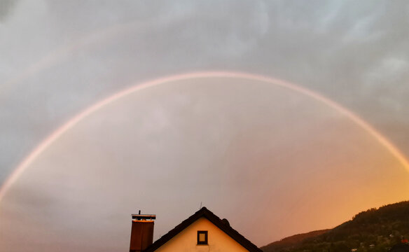 Ein runder Regenbogen &uuml;ber einem Haus