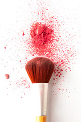 A smashed pink blush powder with make up brush on a white background
