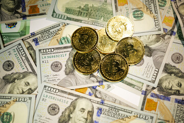 Gold Bitcoin on hundred dollars bills. Close-up