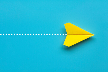 Top view of yellow paper airplane on blue background