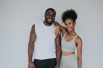 Happy smiling healthy couple in fitness wear standing against white background
