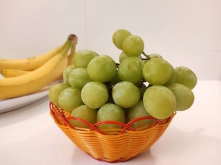 Green grapes in a small basket isolated on white background