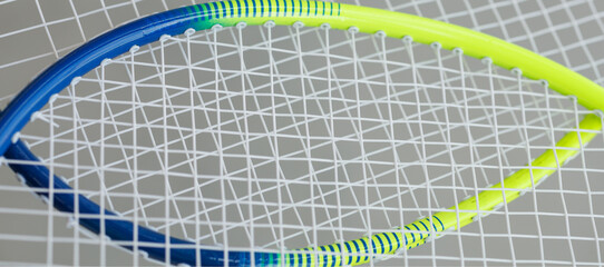 crossed yellow and blue tennis rackets with stretched cuts
