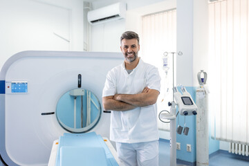 Confident male doctor oncology in magnetic resonance imaging or computed tomography room of a...