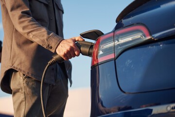 Conception of green energy. Man is standing near his electric car outdoors