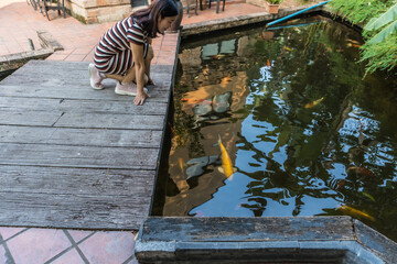 A woman watching over the koi under the pool