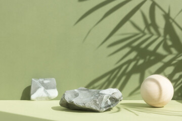 An empty podium made of gray stone with a wooden ball on a green background with a shadow of tropical leaves. Scene for the promotion of products, beauty, natural eco-cosmetics. Showcase, display case