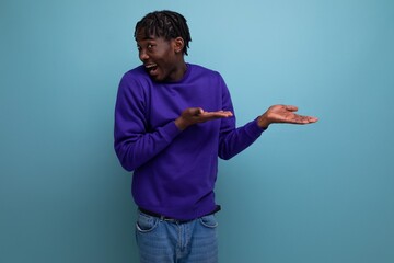 doubtful dark-skinned american african young brunette man with dreadlocks in a blue hoodie