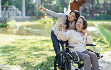 Asian senior woman in wheelchair with happy daughter. Family relationship retired woman sitting on...