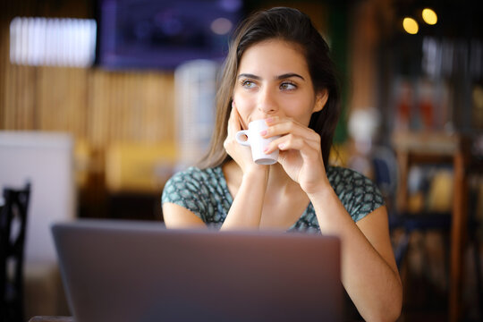 Woman using laptop drinking in a coffee shop