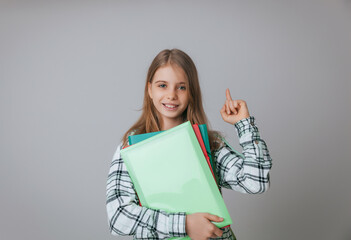Close-up portrait of a little schoolgirl.girl 11,12,13 years old holds a folder for papers on a gray background. copy space