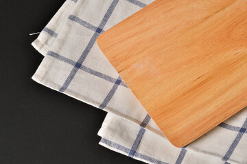 Wood Tray with striped fabric on black background.Empty wooden serving board with napkin on a dark background. 
