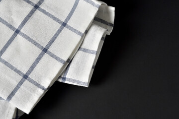Black table with striped fabric kitchen towel. textile napkin flat lay. gingham tablecloth on black background. Copy space for text.for advertisement graphic design.
