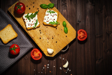 Breakfast photo of cream cheese and bread sliced. Tomato on wooden background.