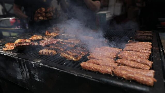 Romanian traditional mici (mititei), grilled ground meat rolls in cylindrical shape and other meats on the barbecue grill.