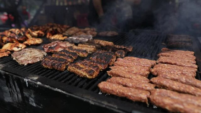 Romanian traditional mici (mititei), grilled ground meat rolls in cylindrical shape and other meats on the barbecue grill.