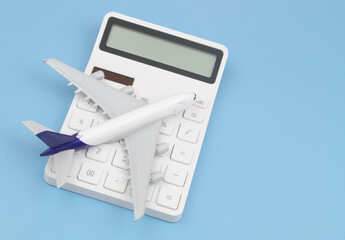 Shipping and delivering cost concept. Airplane on white calculator on blue background close up.