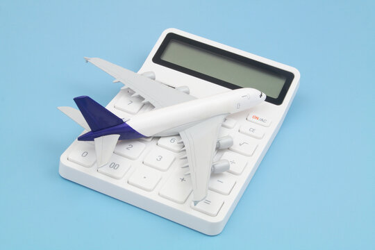 Shipping and delivering cost concept. Airplane on white calculator on blue background close up. 