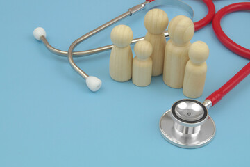 Family wooden people figures and stethoscope on blue background. Family doctor concept. Copy space for text.