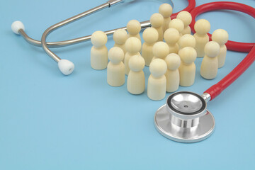 Many wooden people figures with red stethoscope on blue background. Copy space for text.