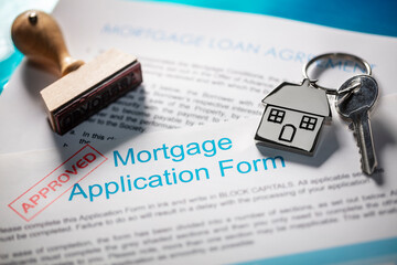 House key on keyring with mortgage application form and loan agreement