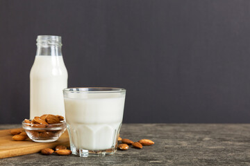 Top view of the almond milk in the glass bottle with almond nuts on the colored table. top view vith copy space
