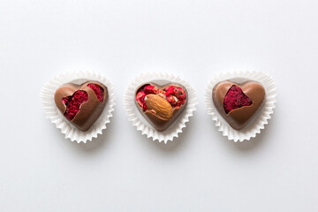 chocolate sweets in the form of a heart with fruits and nuts on a colored background. top view with space for text, holiday concept