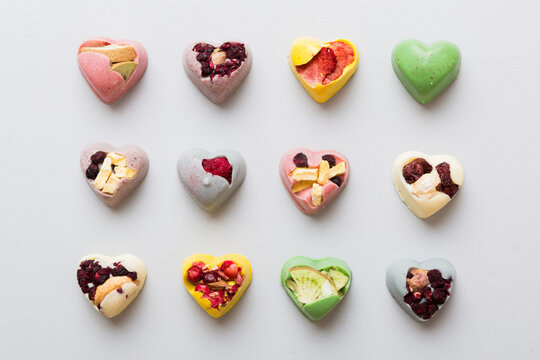Naklejka chocolate sweets in the form of a heart with fruits and nuts on a colored background. top view with space for text, holiday concept