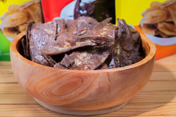 Banana chips with chocolate flavor made from raw bananas fried in a wooden bowl. Traditional snacks
