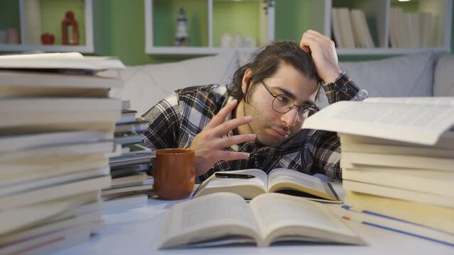 The tired young man is tired of looking at the books.