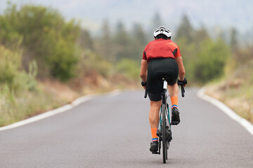 Fototapeta na wymiar Male cyclist riding racing bicycle, man cycling on countryside summer road. Training for triathlon or cycling