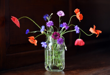 Glass with poppies and cornflowers