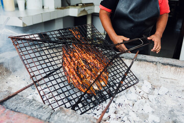 hands of Mexican man cooking grilled fish traditional from Acapulco Mexico or barbecued fish called...