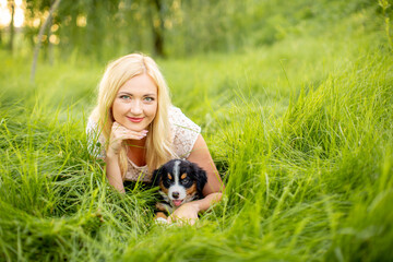 A beautiful girl with a Bernese Mountain Dog puppy is playing in nature. Love for dogs. Animal protection concept. Pet on a walk