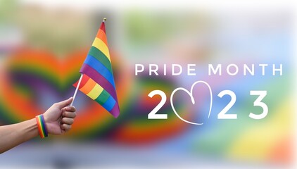 'Pride Month 2023' on blurred rainbow flag and wristband background, concept for lgbtq+ people...