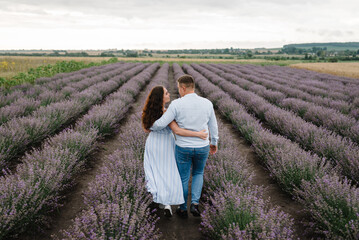 Couple hugging in violet lavender field of flowers. Man and woman standing, enjoys floral glade,...