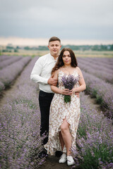 Couple standing and enjoys floral glade, summer nature. Loving couple holding bouquet of lavender flowers at sunset. Family hugging in violet lavender field. France, Provence. Honeymoon trip. Closeup.