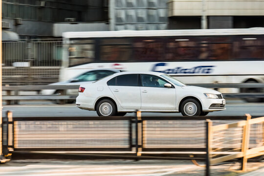 Volkswagen Jetta sixth generation car moving on the street. White Volkswagen Sagitar, codenamed A6 rushing on city road, side view