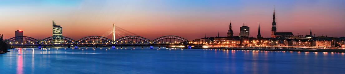 Panoramic night view across river of Riga, Latvia. Copy space in sky and water.