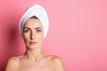 young woman with towel on head, nude shoulders on pink background