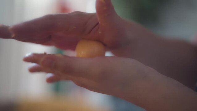 Chef's hands rolling traditional Brazilian cheese bun in her hands. Slow motion, shallow depth of field.  