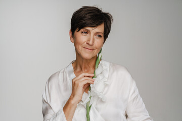Senior woman posing with gladiolus flower isolated over white background