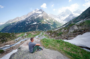 Naklejka na ściany i meble Travel by Swiss Alps. Young man enjoying the mountains view.