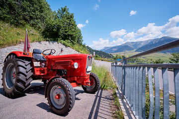 Renovated and repainted vintage retro old small compact utility tractor with new tyres parked with mountains view.