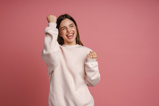 Excited woman screaming and celebrating success isolated over pink background