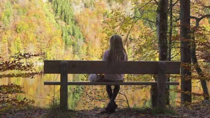 child girl sitting on the bench at the autumn park near the lake - Powered by Adobe