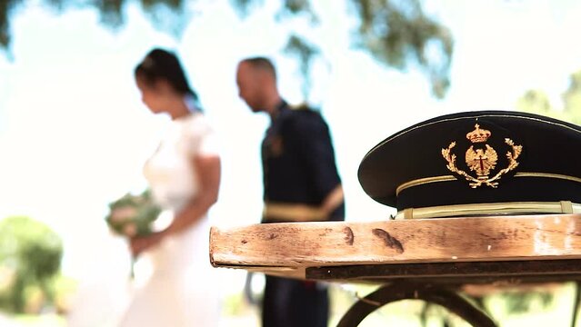 Military hat in the foreground and a wedding out of focus in the background.