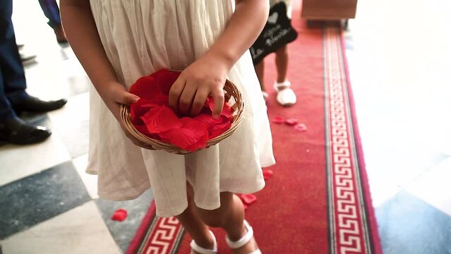 Girl throwing red rose petals on the floor at a wedding.